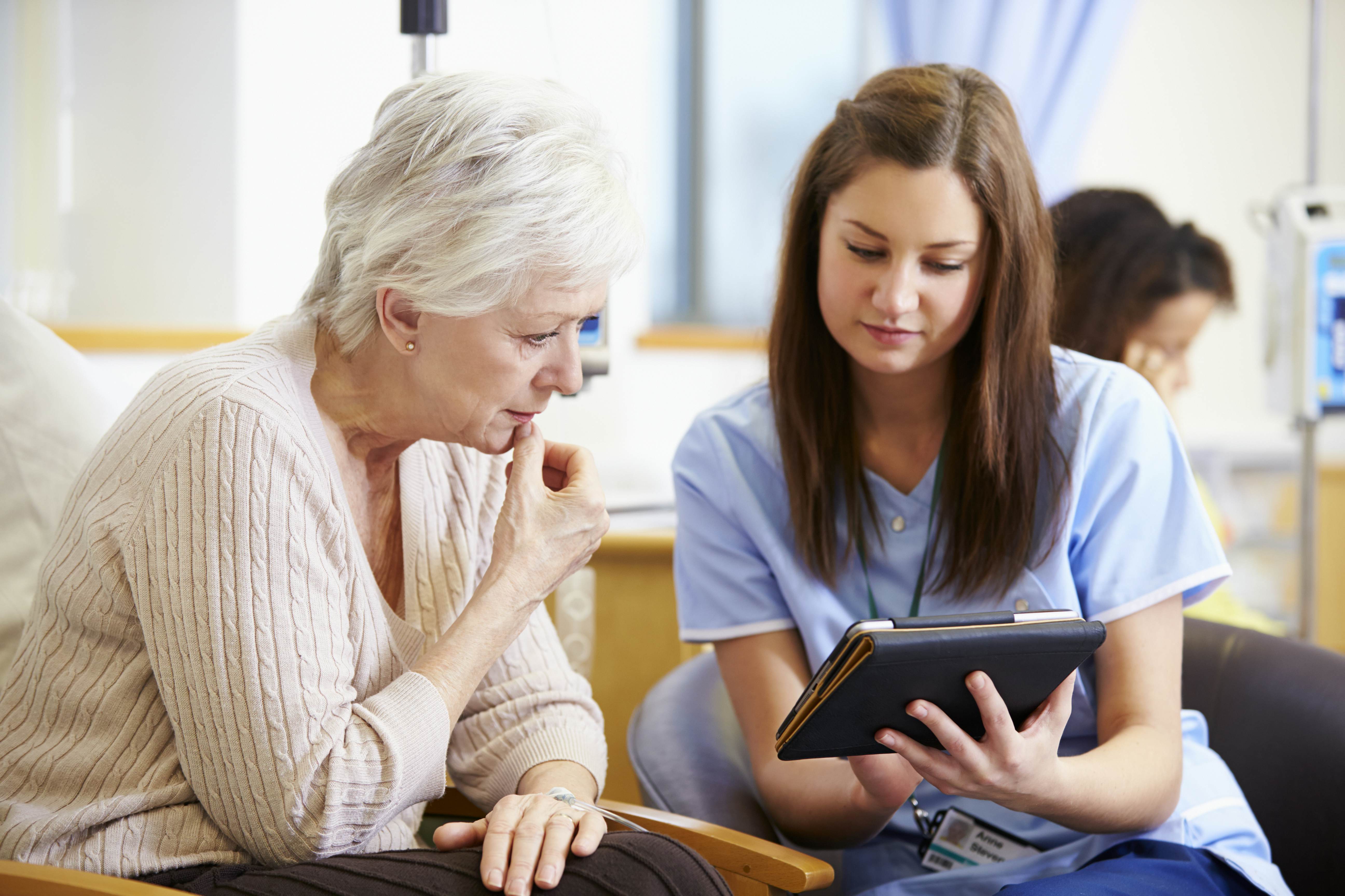 Nurse sharing data with patient using a tablet. Study Nursing abroad.
