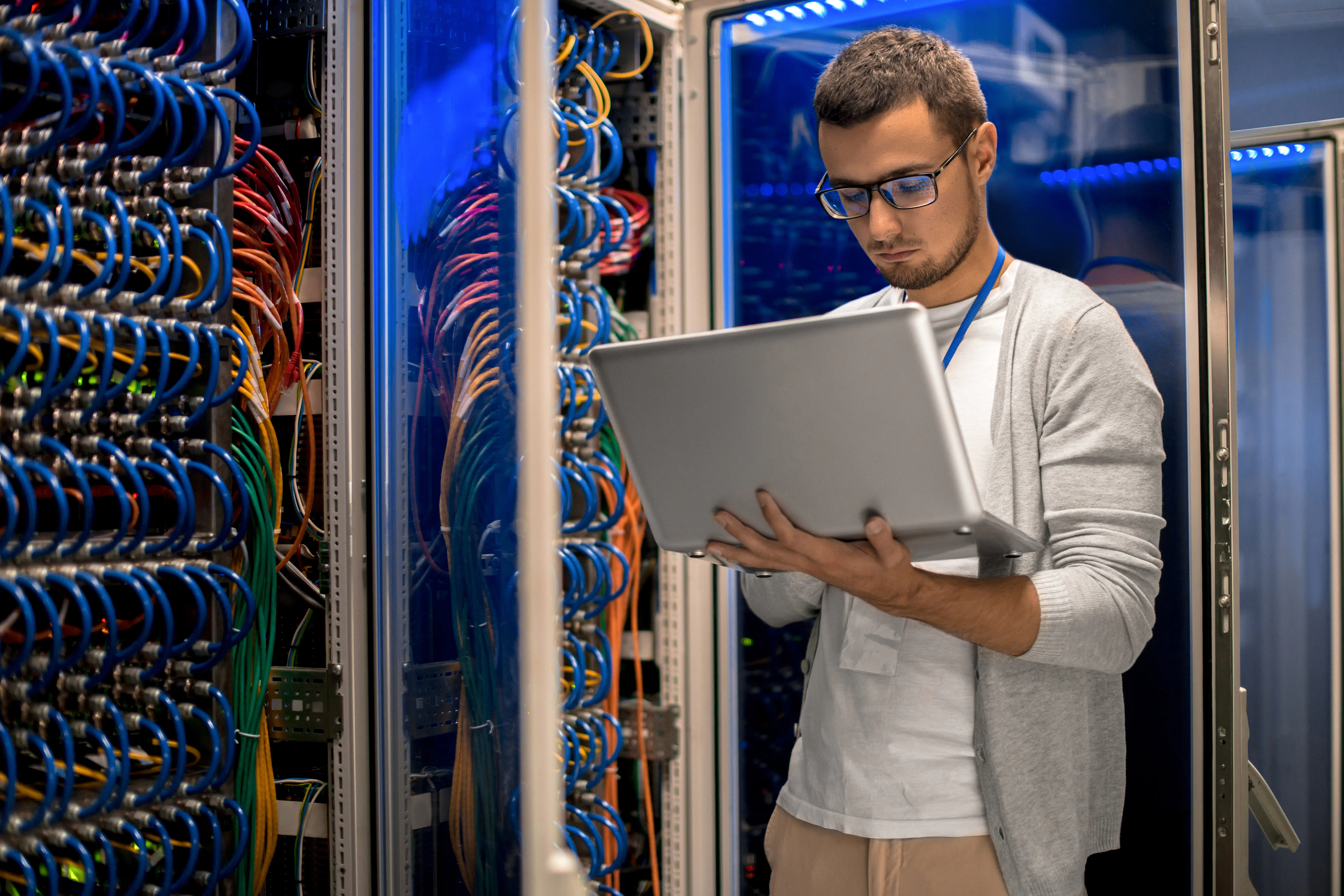 Computer scientist working on a laptop in a server room