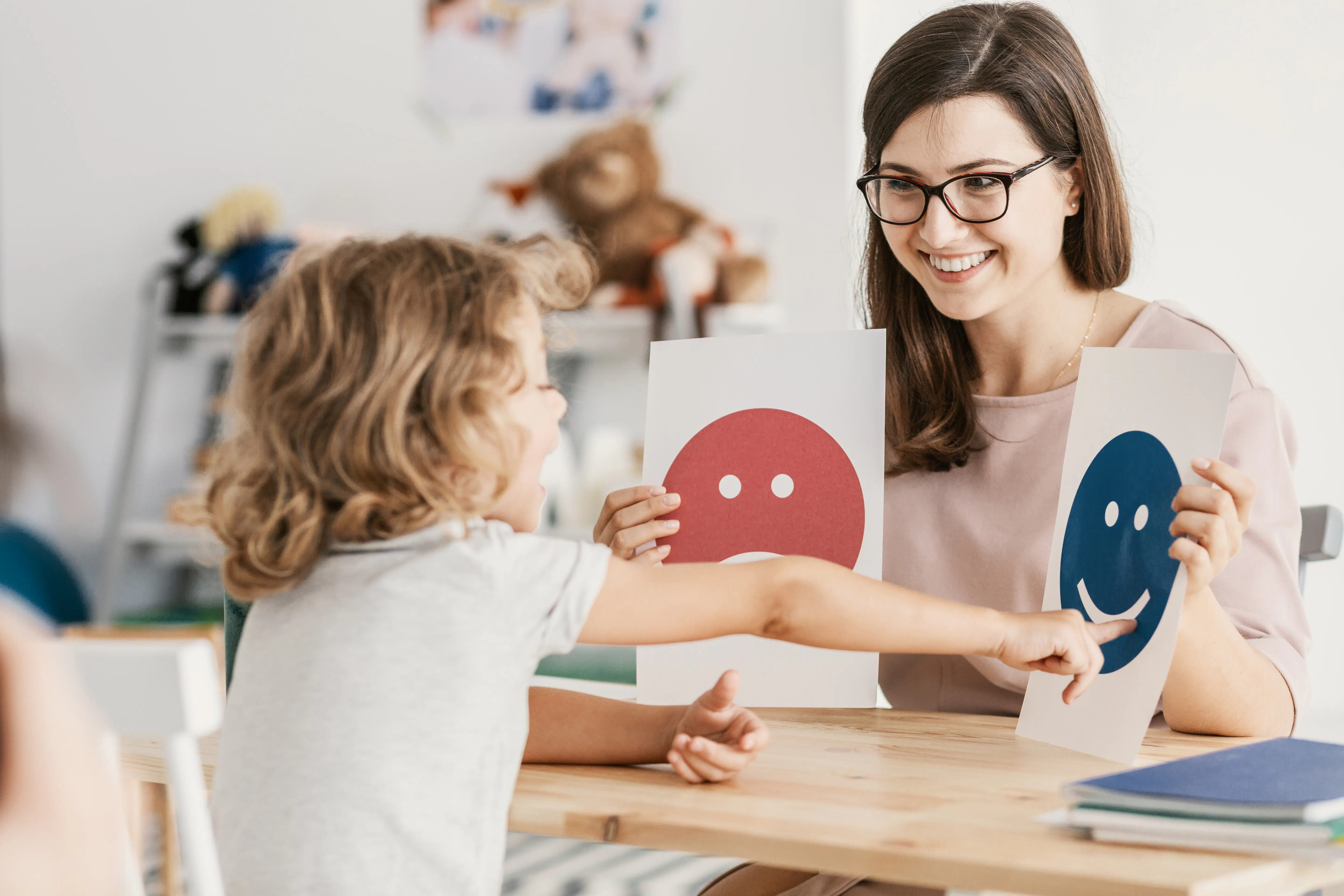 Psychologist uses emotion emoticons during a therapy session with a child