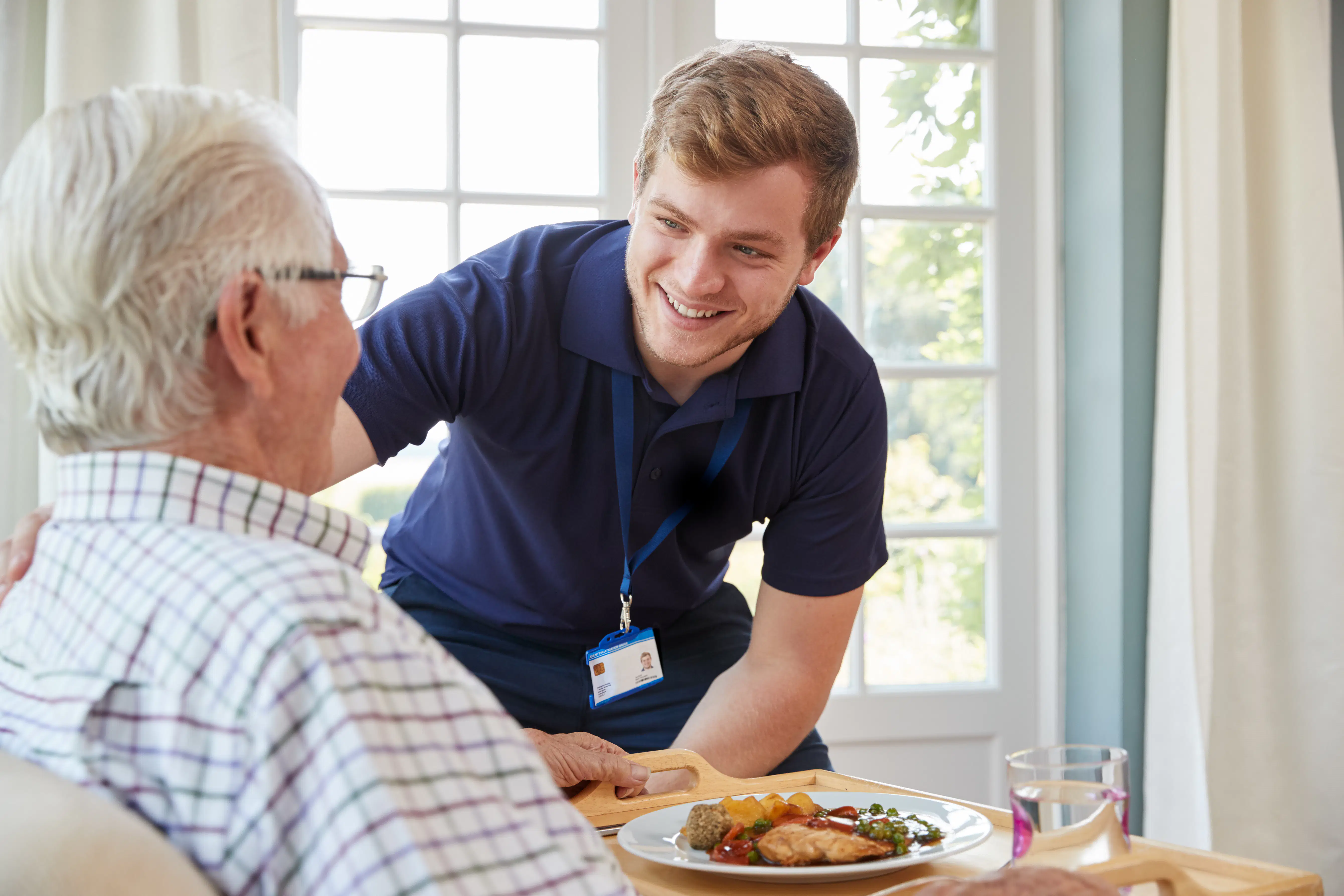 Nurse serves lunch to senior man