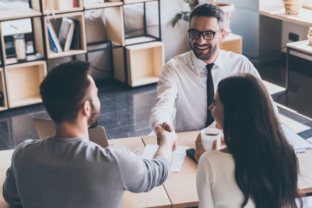 Financial planner shakes hands with young couple